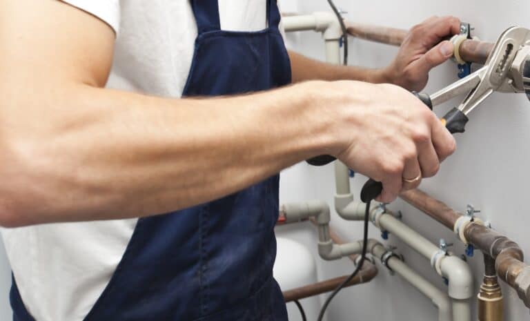 Professional plumber repairing pipes with a pipe wrench to ensure clean pipes and a clean home.